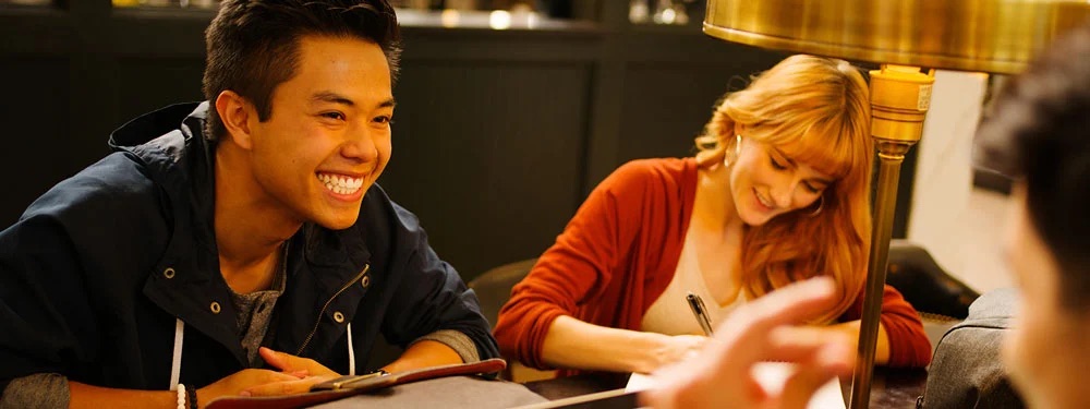 Students in a library sitting around a table studying notes