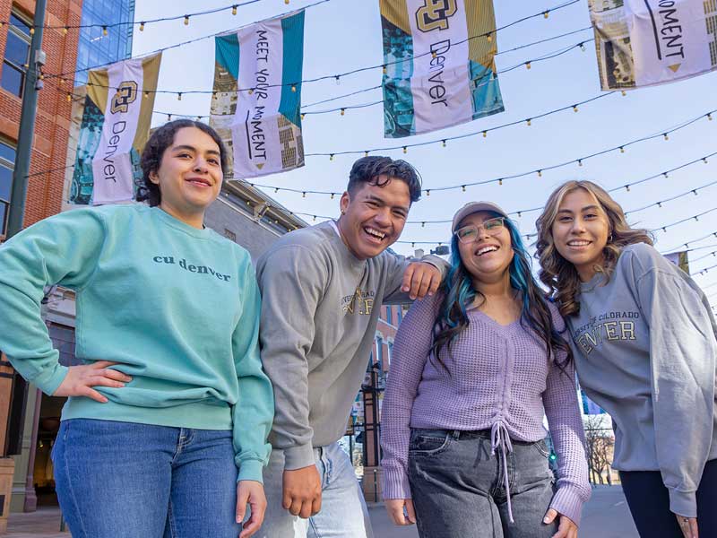 CU Denver students posing for image in Larimer Square under CU Denver flags