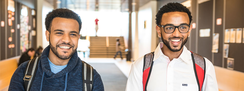 Two CU Denver students smiling while walking through campus hall