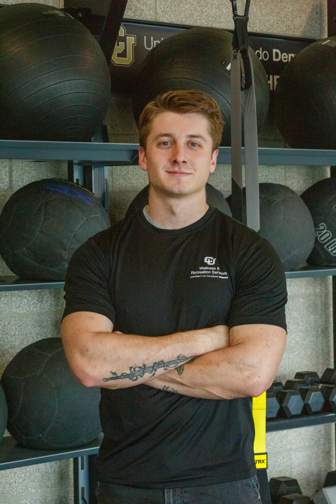 headshot of Aaron Rankin - man with a black shirt crossing his arms in a gym