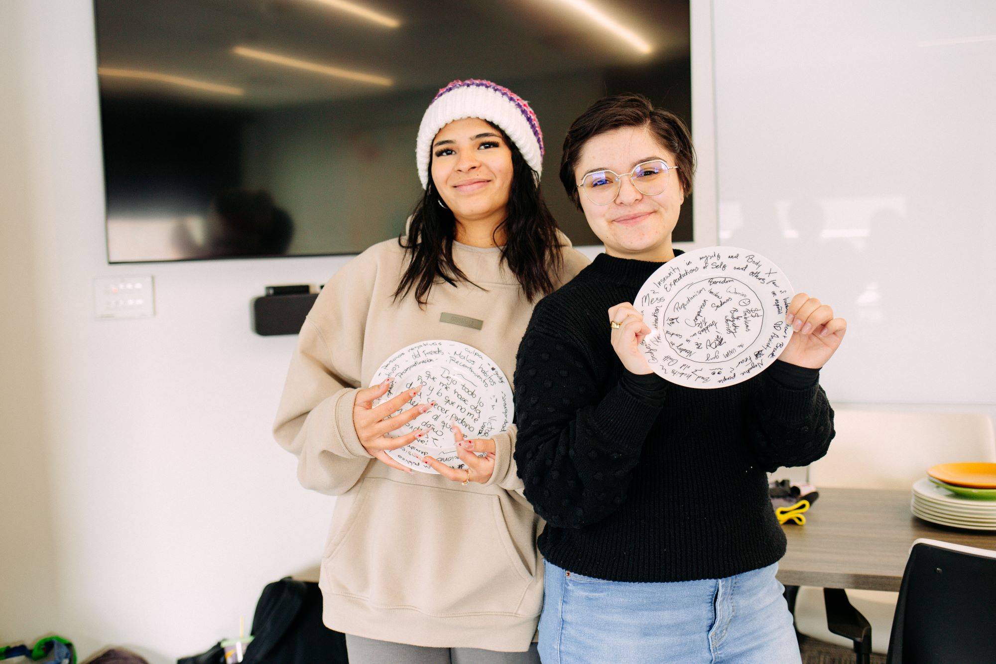two girls smiling and holding up plates