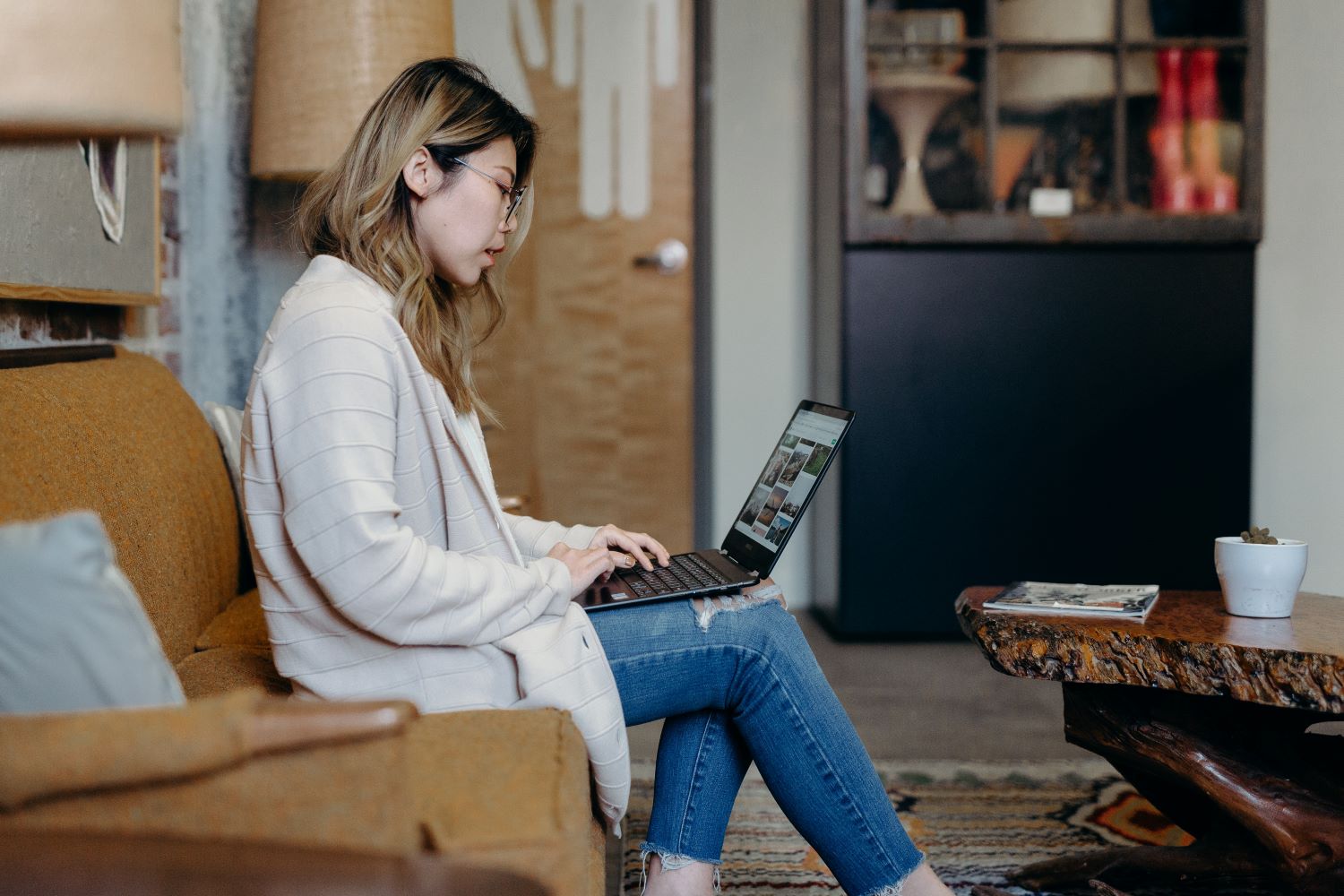 Woman sitting on couch with computer open on lap.