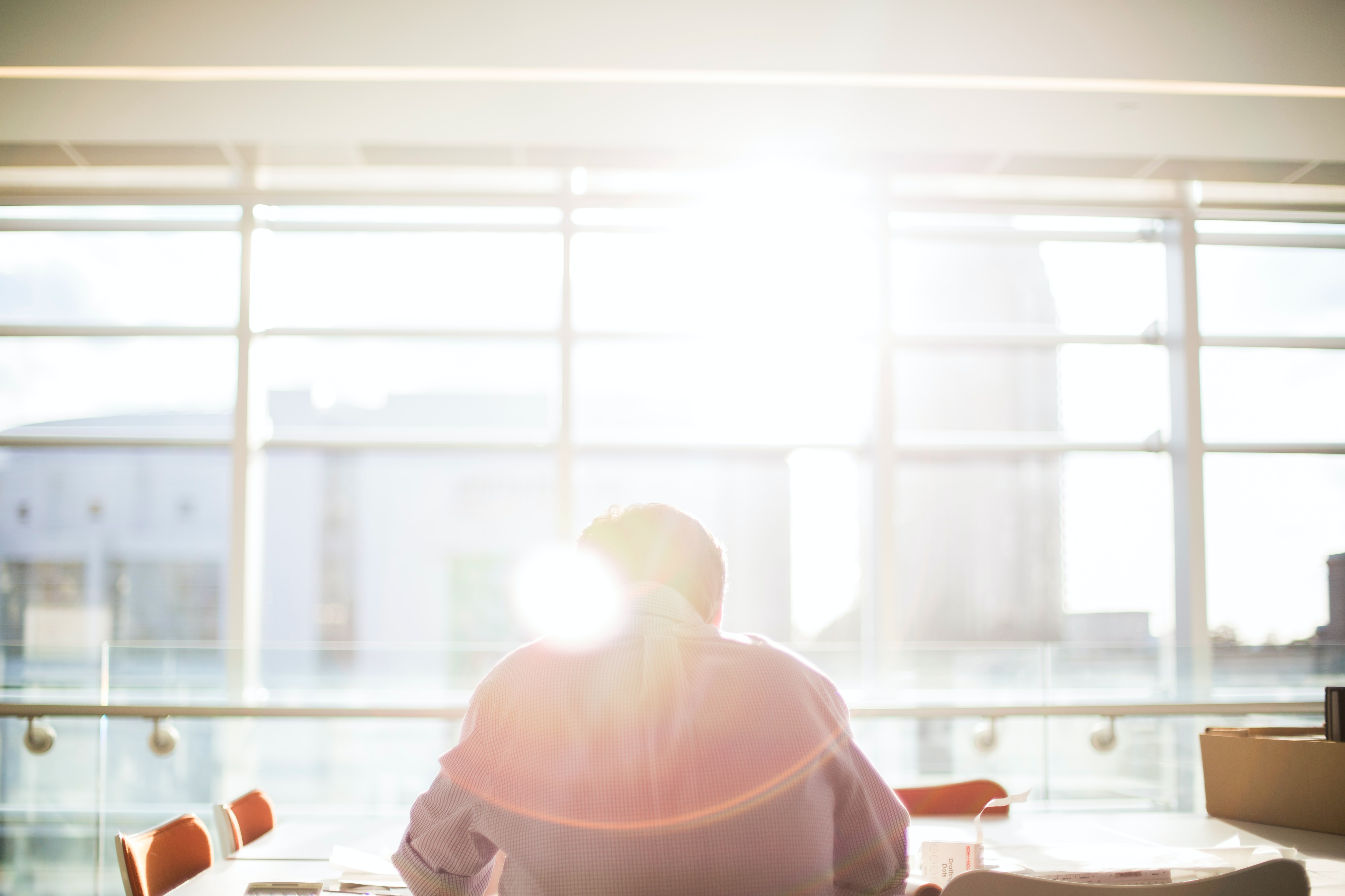 person sits at desk studying and working with sunlight coming in from windows