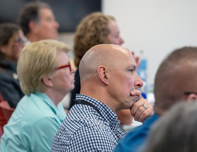 Side view of rows of people seated and watching a presentation.