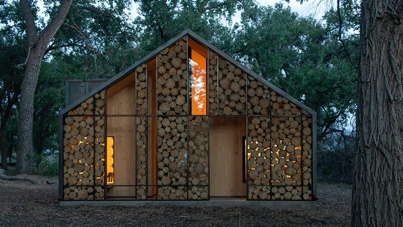 Cabin in the woods made of metal framing and stacked logs.
