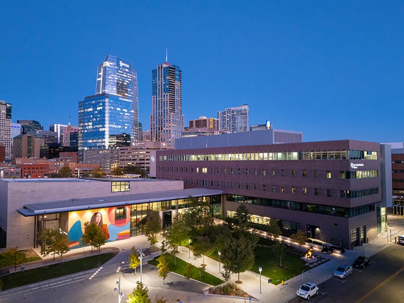 Aerial view of the Student Commons Building and Denver skyline in the background at night.