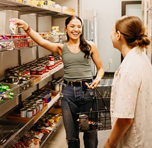 Two people shopping in a food pantry smiling.
