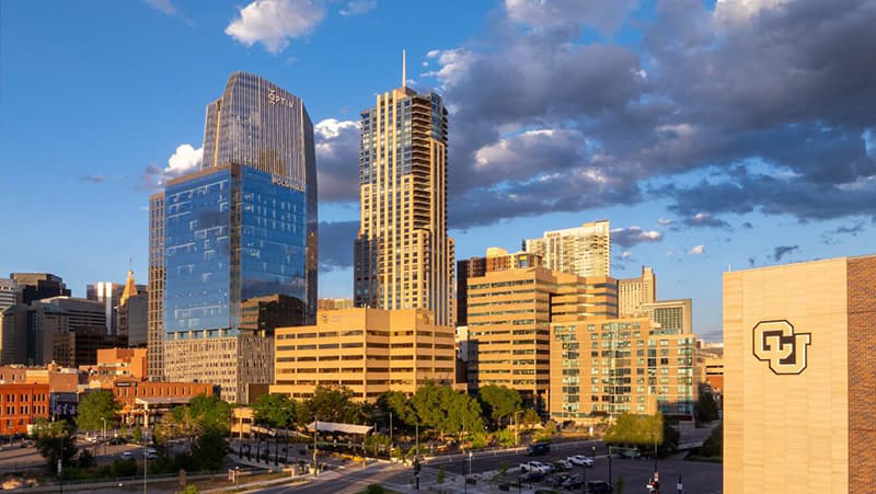 Aerial view of Lower Downtown Denver with a large interlocking CU sign on a building in the foreground.