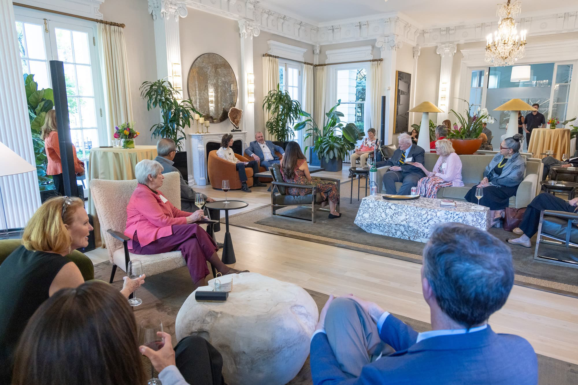 Group of people seated on couches and chairs in a large room.