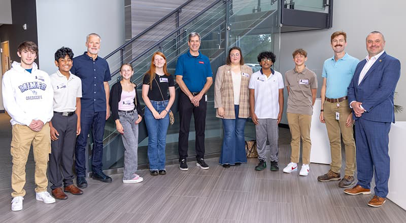 Group of 11 people, staff and students, lined up and smiling. 