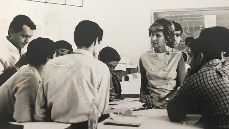 Dr. Puggioni speaking to a group of students in a classroom setting, in black and white.
