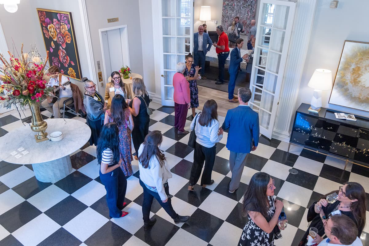 Overhead view of people in professional business attire mingling. The floor is black and white checkered. 
