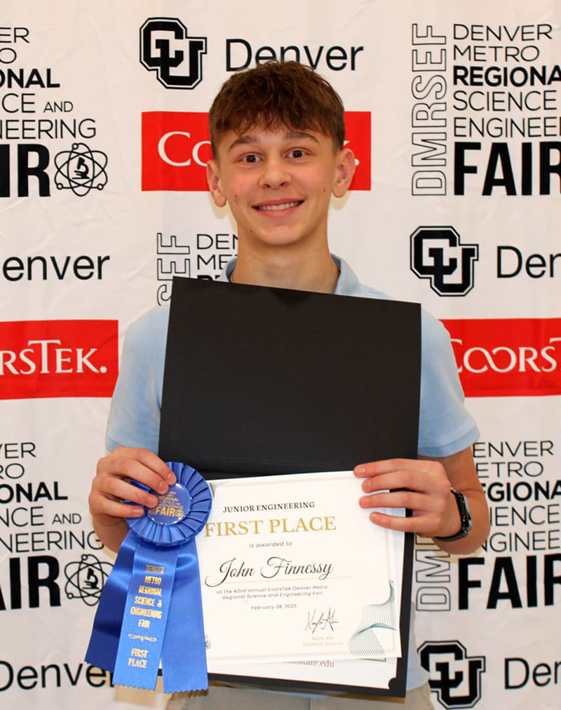 Young boy proudly holds a first place certificate with his name on it.