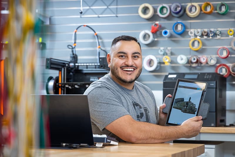 A man working in a lab holding up an iPad with a rendering. 