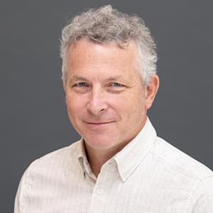 Man in a white collard shirt with a closed-mouth smile.