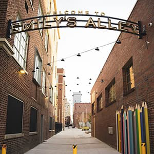 Entrance to Emily's Alley between two brick buildings and a big arched sign.