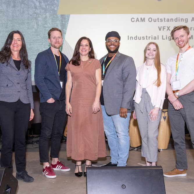 Group of six people smiling together dressed in business attire.