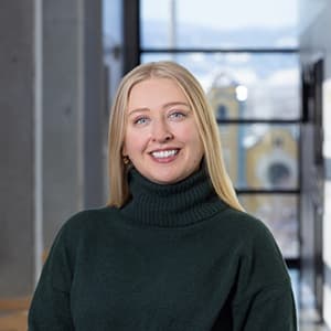 Woman in a black turtleneck and long blonde hair smiles with her teeth.
