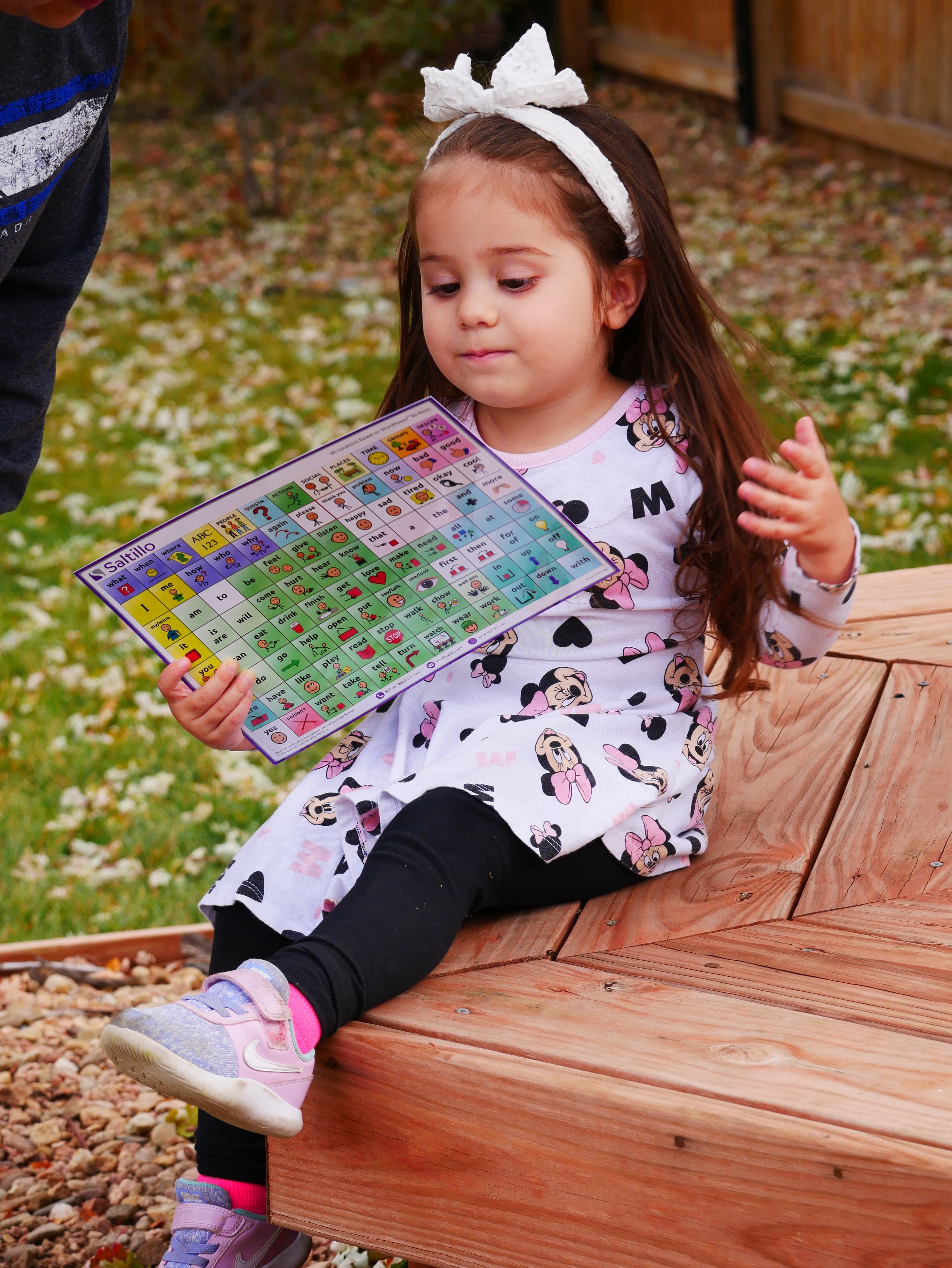 A little girl using an AAC printout