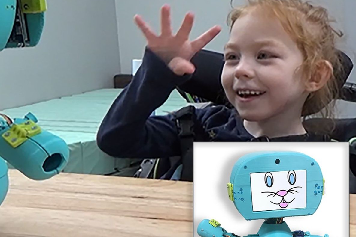 A young girl smiles broadly while interactive with a social robot designed by CIDE engineers.