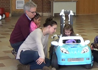 CIDE researchers work with a young girl learning to drive in a motorized toy car using adaptive switches..
