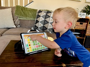 aac device a boy tapping on the screen of an aac device with open communication software