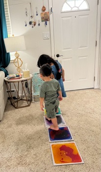 two children standing on two of four sensory floor tiles